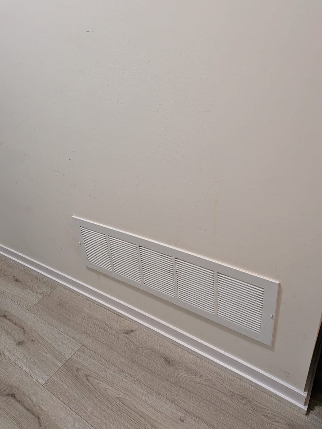 A cleaned baseboard and floor vent along a wood floor
