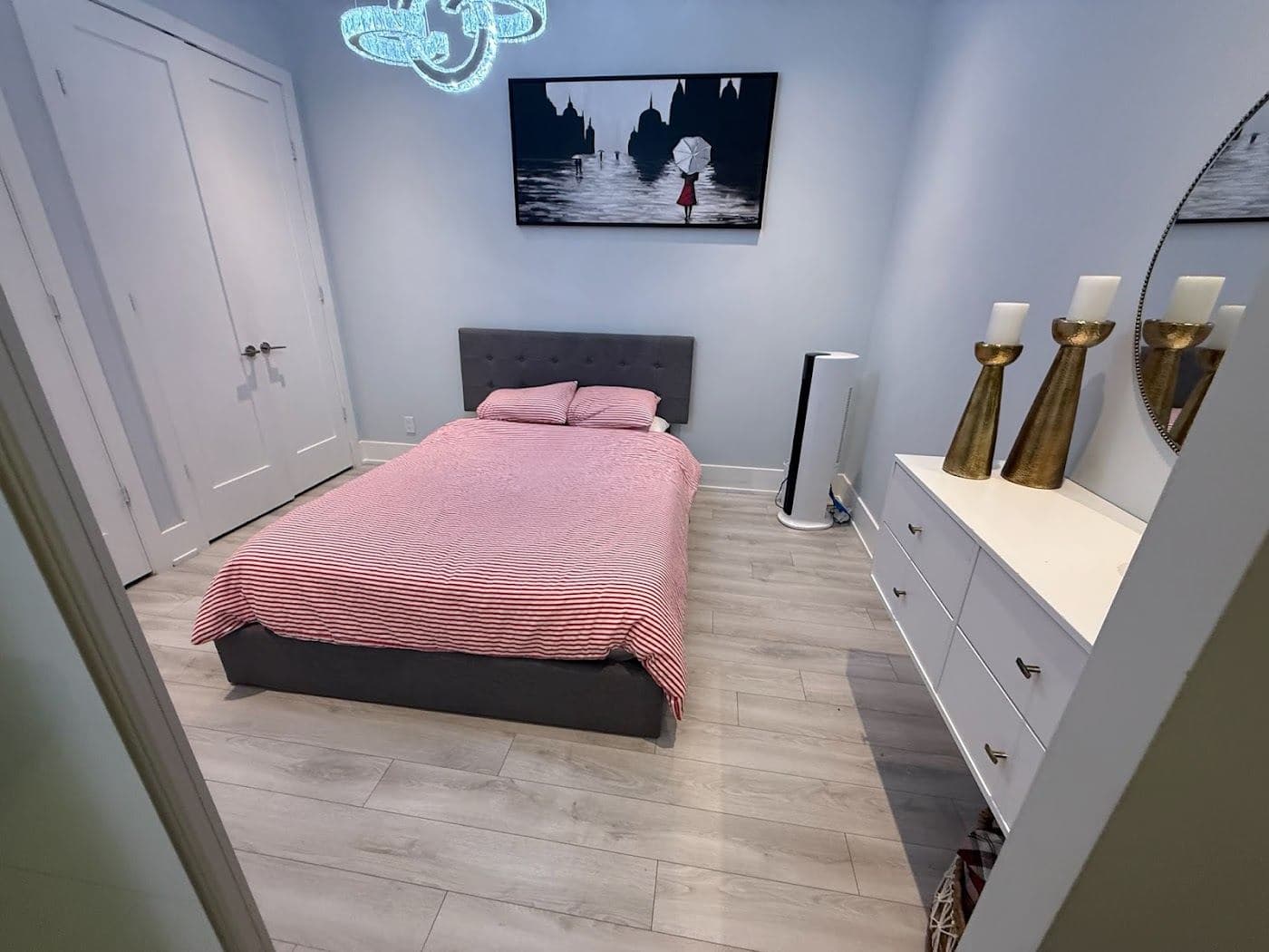 A bedroom with a made bed and a framed picture above it