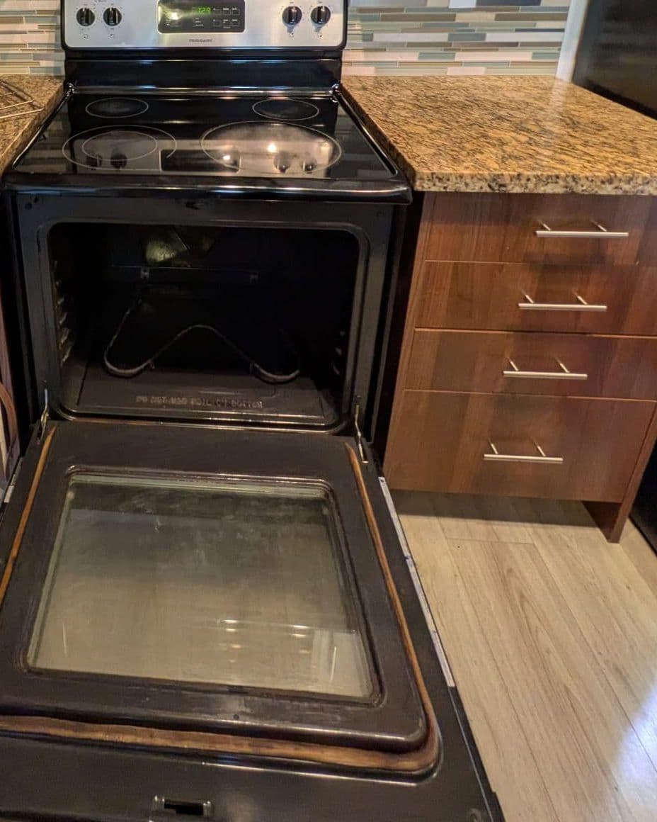 The same oven open after cleaning, with a clean floor and door glass